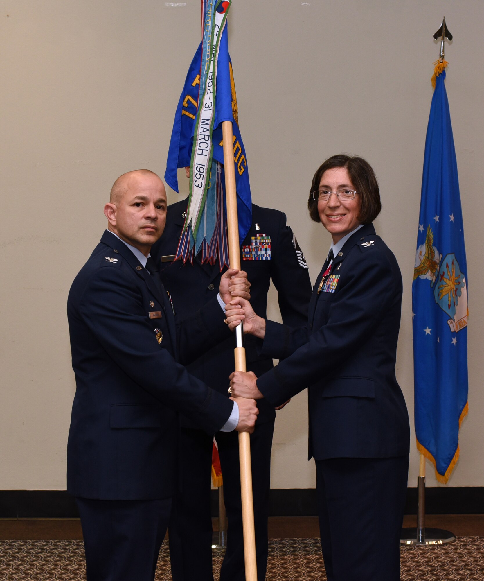 U.S. Air Force Col. Janet Urbanski, 17th Medical Group outgoing commander, formally relinquishes her command by handing Col. Andres Nazario, 17th Training Wing commander, her guidon during the 17th MDG Change of Command Ceremony held at the event center on Goodfellow Air Force Base, Texas, July 8, 2019.  Urbanski led over 200 military, civilian and contract employees to serve thousands of beneficiaries and students in healthcare missions during her two years of service at Goodfellow. (U.S. Air Force photo by Airman 1st Class Abbey Rieves/Released)