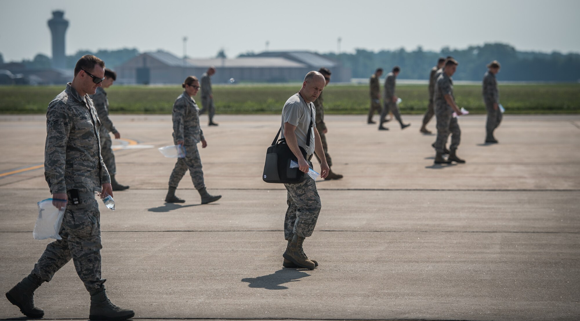 Master Sgt. Jonathon Tolbert, 375th Air Mobility Wing foreign object debris monitor, center,  walks the flightline looking for possible aircraft damaging debris with fellow Team Scott Airmen during the weekly FOD walk, July 9, 2019, Scott Air Force Base, Illinois. (U.S. Air Force photo by Christopher Parr)