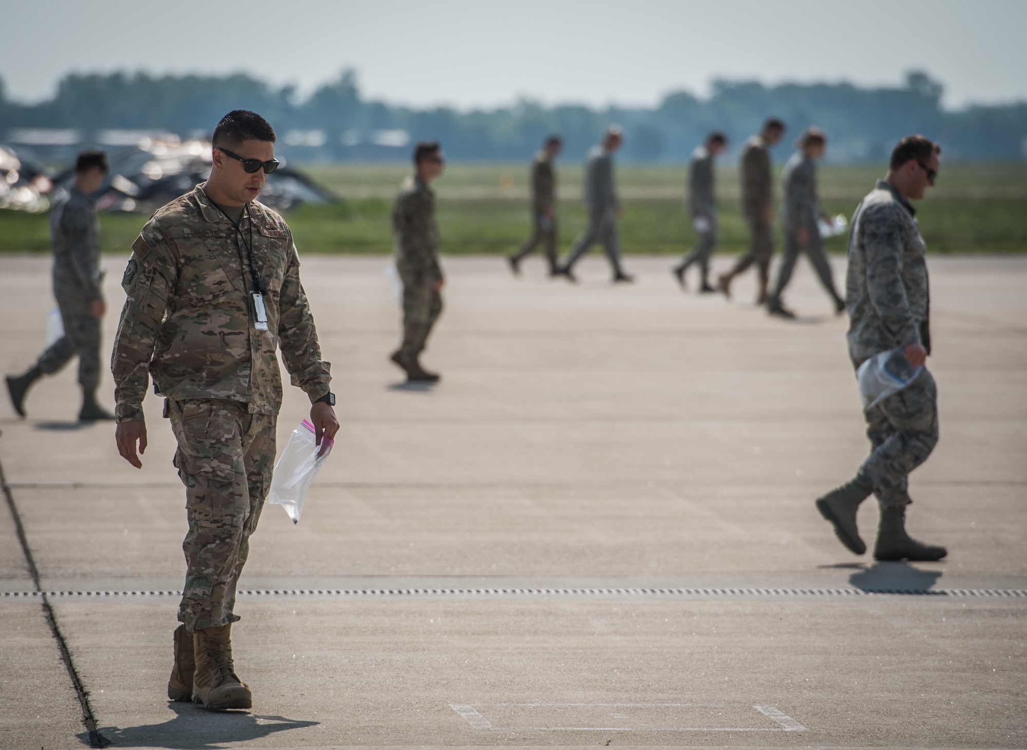 Master Sgt. Sandro Cardona, flightline expediter, 932nd Airlift Wing Maintenance Squadron,  along with Team Scott Airmen, scans the flightline for debris during the weekly foreign object debris (FOD) walk, July 9, 2019, Scott Air force Base, Illinois. (U.S. Air Force photo by Christopher Parr)