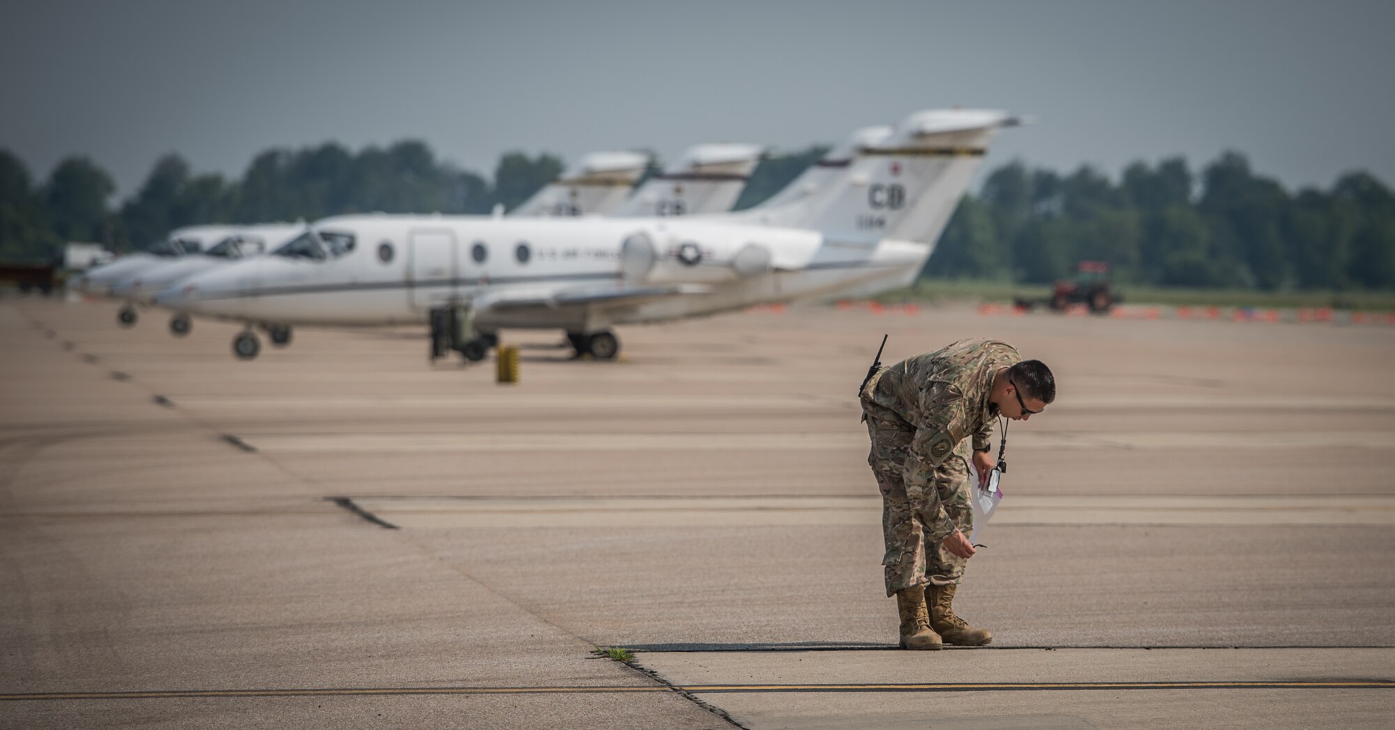 Master Sgt. Sandro Cardona, flightline expediter, 932nd Airlift Wing Maintenance Squadron, picks up potentially hazardous debris from the flightline during the weekly foreign object debris (FOD) walk, July 9, 2019, Scott Air force Base, Illinois.  FOD can be harmful to aircraft if it is sucked into the engines, possibly causing damage to the high-precision engines and other vital systems. (U.S. Air Force photo by Christopher Parr)