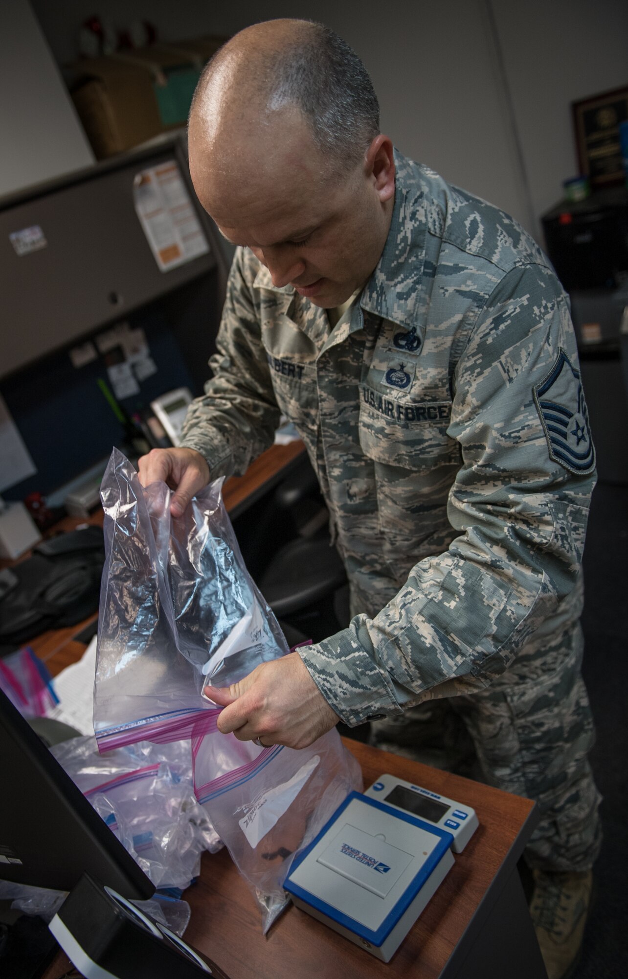 Master Sgt. Jonathon Tolbert, 375th Air Mobility Wing foreign object debris monitor, combines debris into one bag that was collected during the weekly FOD walk, July 9, 2019, Scott Air Force Base, Illinois.  The  debris is then weighed and logged to maintain a record of all debris collected throughout the year. (U.S. Air Force photo by Christopher Parr)