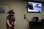 Computer Engineer Daniel Stith shows how to use the hands-free headset for the virtual reality simulation.