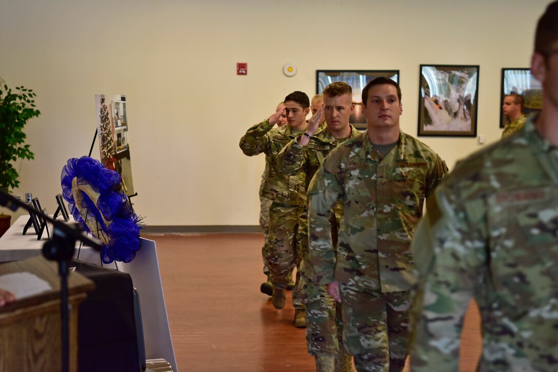 Members of the 11th Security Forces Squadron salute as they walk past a memorial for Military Working Dog, Tommy, during a memorial ceremony at the Community Commons on Joint Base Andrews, Md., July 3, 2019. JBA has 27 dogs in their kennels ranging from explosive detection to narcotics and patrol. (U.S. Air Force photo by Airman 1st Class Noah Sudolcan)