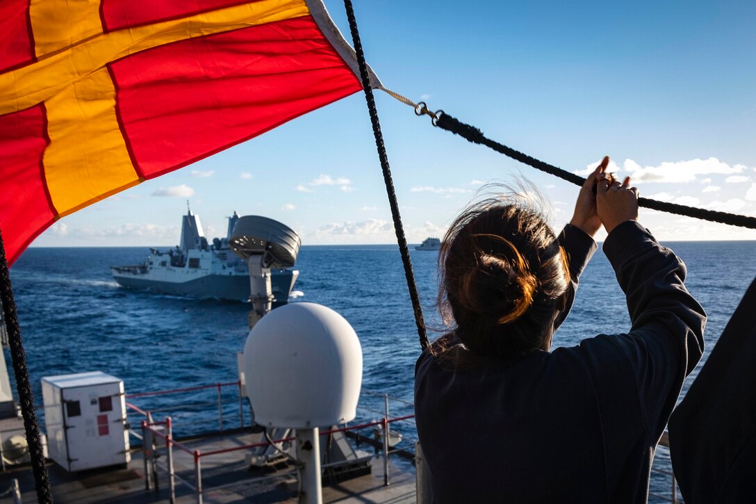 A sailor holds onto a flag.