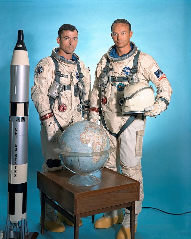 Men pose beside rocket model