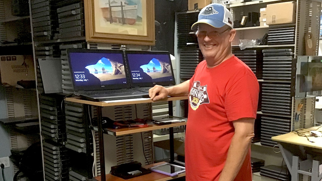 John Luedke stands in front of two laptop computers and several other devices