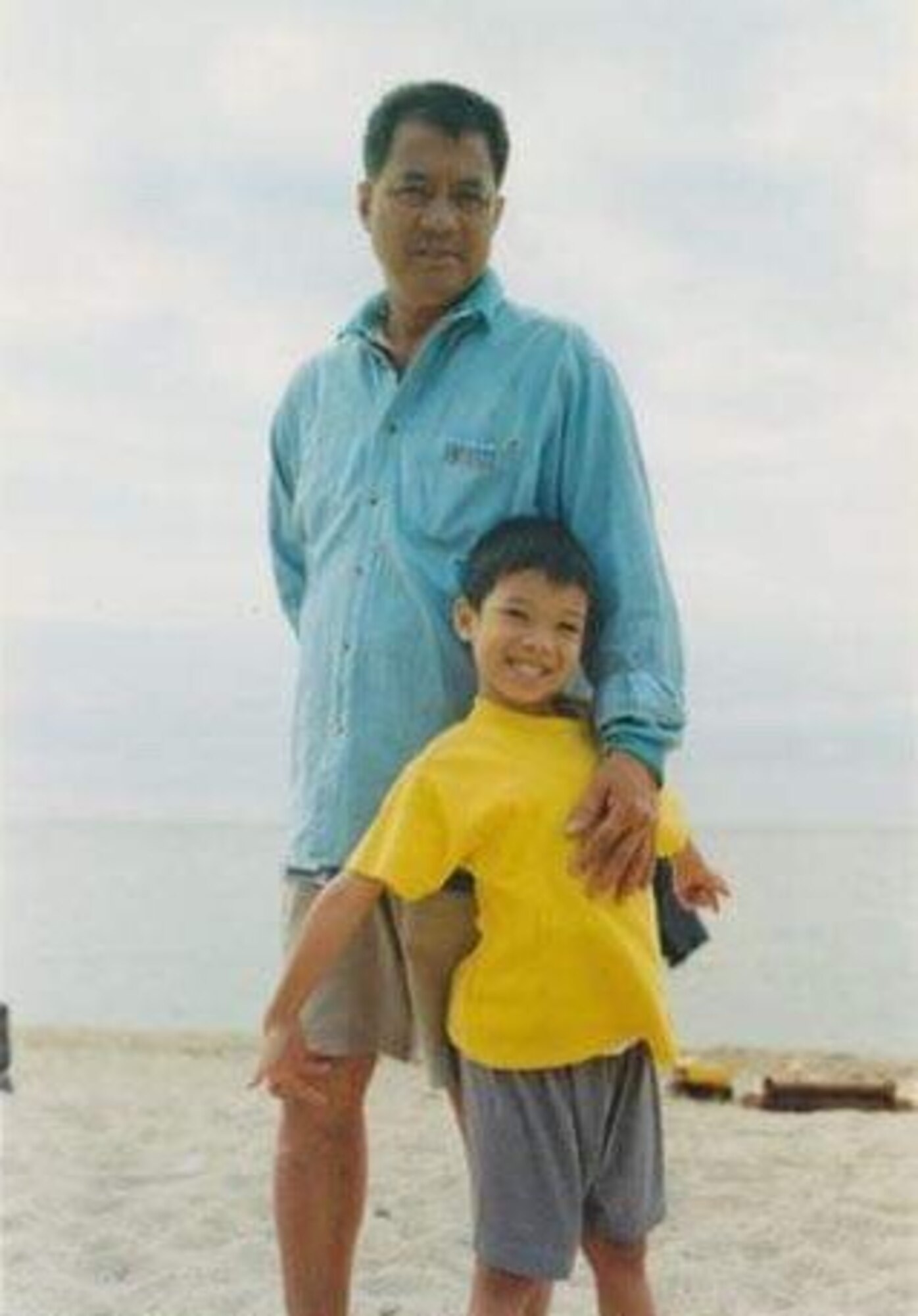 Boy stands with grandfather on the beach in the Philippines