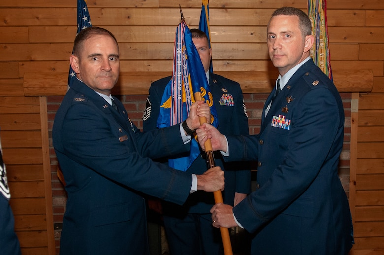 Col. Hewett Wells, 50th Network Operations Group commander, passes the guidon to Lt. Col. Dan Highlander, incoming 23rd Space Operations Squadron commander during a change of command ceremony at New Boston Air Force Station, New Hampshire, July 2, 2019. 23 SOPS is one of eight Air Force Satellite Control Network Remote Tracking Stations providing United States Strategic Command with critical satellite command and control capability to more than 185 Department of Defense, national and civilian satellites performing intelligence, weather, early-warning and communications operations.