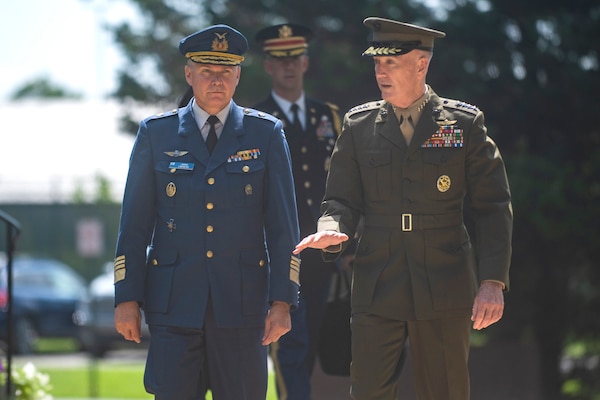 Two military commanders walk together during a ceremony.