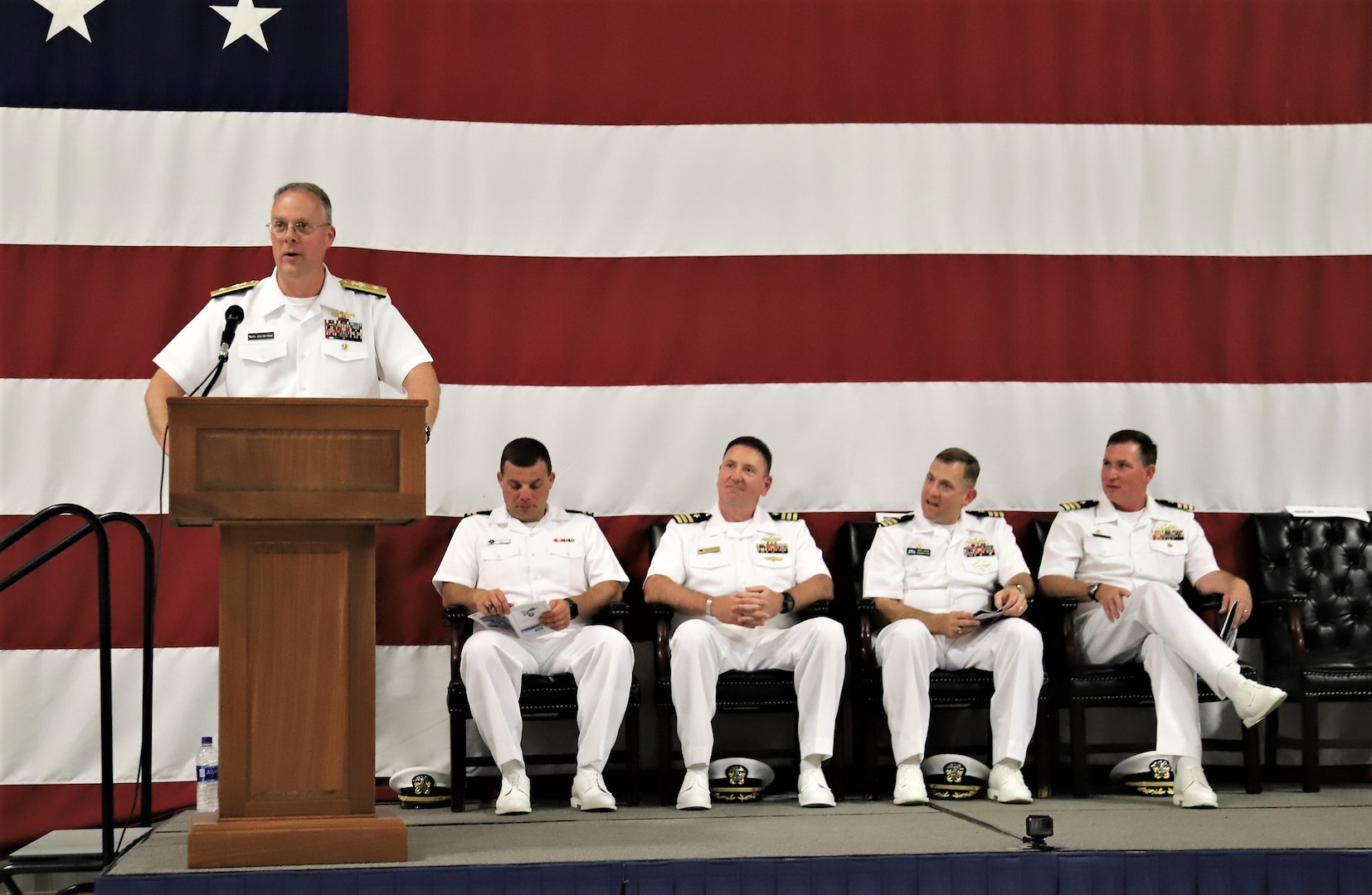 IMAGE: (Far left) Rear Adm. Eric Ver Hage, Commander NAVSEA Warfare Centers, speaks to more than 200 Sailors and guests attending a traditional Change of Command ceremony at Naval Air Station (NAS) Oceana’s Center for Naval Aviation Technical Training Unit’s ceremonial hangar aboard NAS Oceana June 27 where Cmdr. Andrew Hoffman was relieved of command by Cmdr. Joseph Oravec. Oravec became the 28th commanding officer, Naval Surface Warfare Center Dahlgren Division, Dam Neck Activity.