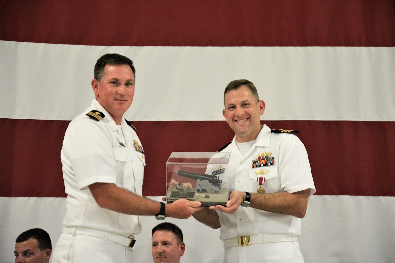 IMAGE: (Left to right) Cmdr. Casey Plew, Commanding Officer, Naval Surface Warfare Center Dahlgren Division (NSWCDD), presents Cmdr. Andrew Hoffman with a farewell “token” for his 40 months as NSWCDD Dam Neck Activity’s commanding officer. More than 200 Sailors and guests attended a traditional Change of Command ceremony at Naval Air Station (NAS) Oceana’s Center for Naval Aviation Technical Training Unit’s ceremonial hangar aboard NAS Oceana June 27 where Hoffman was relieved of command by Cmdr. Joseph Oravec. Oravec became the command’s 28th commanding officer.