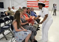 IMAGE: (Center) Chief Logistics Specialist Kisha Vilabrera presents flowers to Cmdr. Joseph Oravec’s wife honoring her role on the home front during a traditional Change of Command ceremony at Naval Air Station (NAS) Oceana’s Center for Naval Aviation Technical Training Unit’s ceremonial hangar aboard NAS Oceana June 27. Oravec relieved Cmdr. Andrew Hoffman and became Naval Surface Warfare Center Dahlgren Division, Dam Neck Activity’s 28th commanding officer.