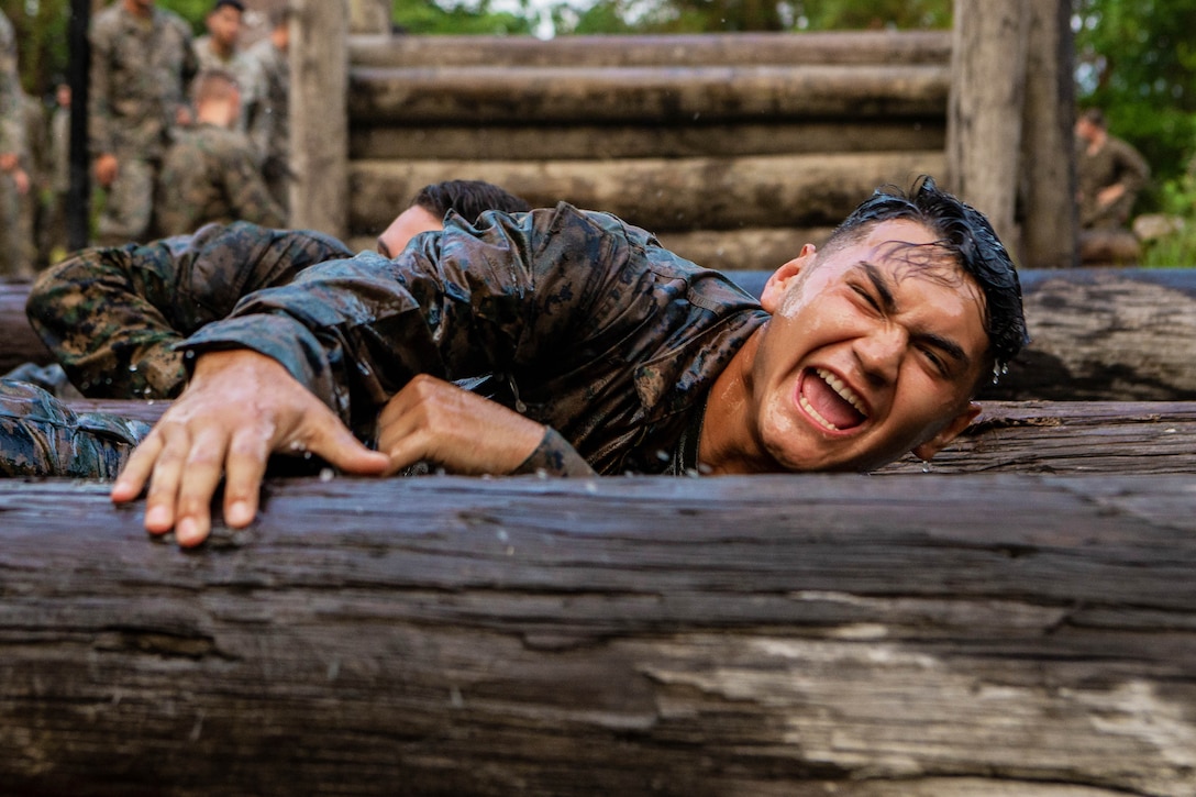 A Marine climbs over an obstacle.