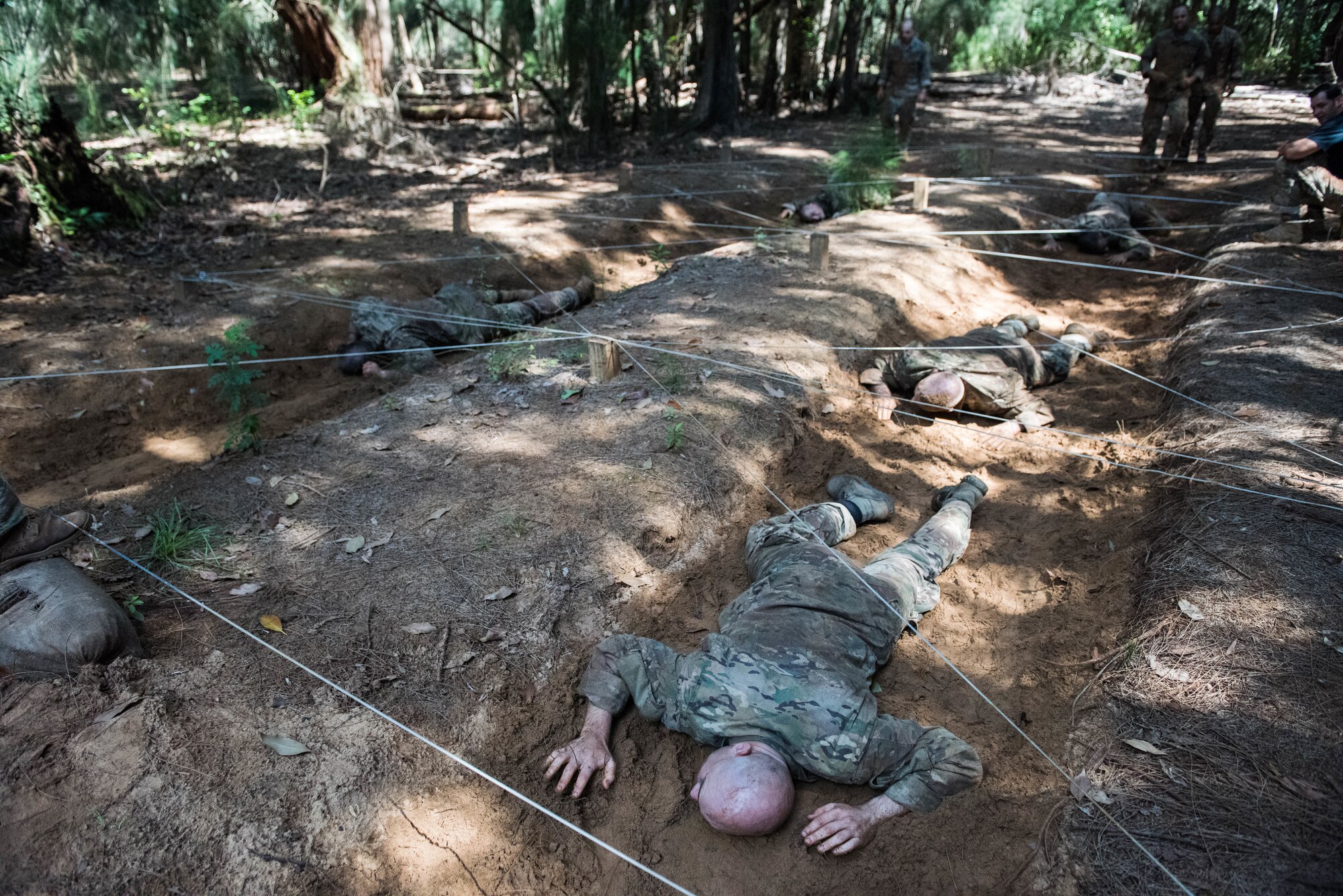 Ranger Assessment Course students low-crawl during the obstacle course for a Ranger Assessment Course near Schofield Barracks, Oahu, Hawaii, May 20, 2019. Throughout the 19-day course, Airmen were tested on their ability to perform land navigation, ambush, react to contact and squad attacks. Along with those assessments, the students went on runs and marches of different distances – all leading up to a 12-mile ruck march two days before graduation. (U.S. Air Force photo by Staff Sgt. Hailey Haux)