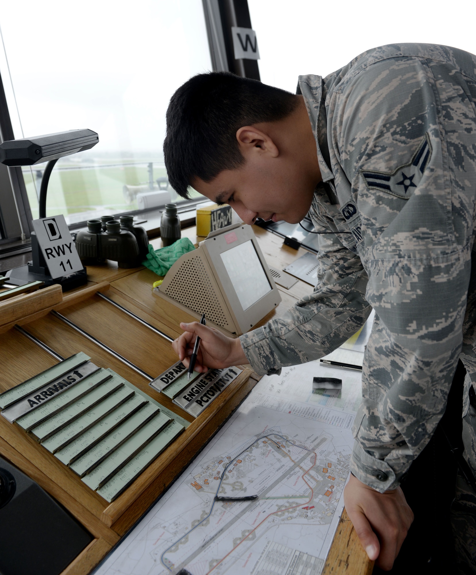 U.S. Air Force Airman 1st Class Luis Iniguez Ramirez, 100th Operations Support Squadron air traffic controller, checks the departure and arrival manifesto inside the air traffic control tower at RAF Mildenhall, England, April 9, 2018. The ever-watching eye of the air traffic controllers from the 100th OSS keeps our skies and aircraft safe. (U.S. Air Force photo by Airman 1st Class Alexandria Lee)
