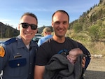 Senior Airman Travis Cunningham(left), 194th Intelligence Squadron, poses with a father and his newborn child near Winthrop, Wash., May 13, 2019. Cunningham, also a Washington State Trooper, helped deliver the baby on the side of the road after a traffic stop turned into a medical emergency.
