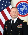 army soldier standing in front of a flag.