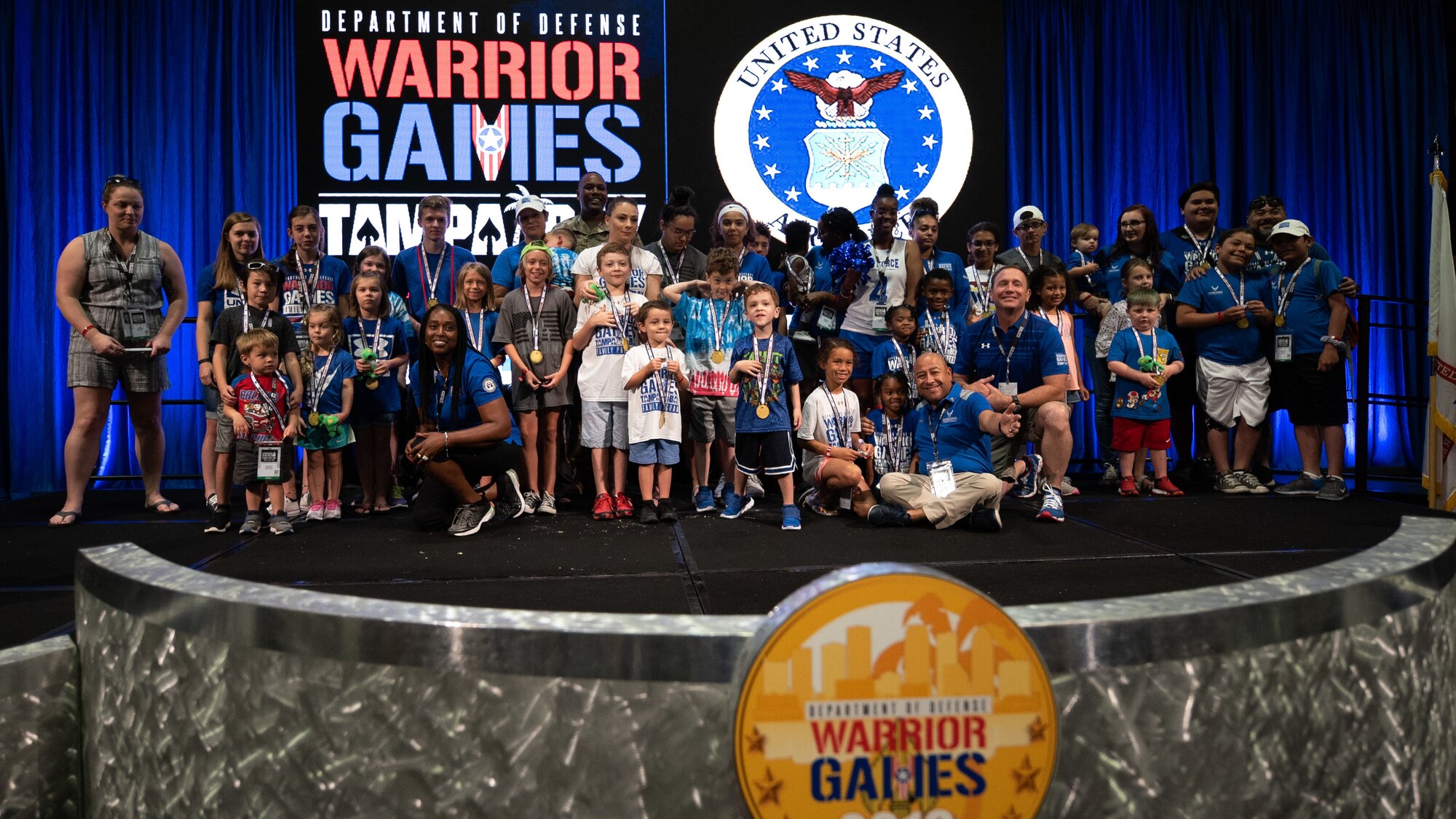 Children of Team Air Force athletes join U.S. Army Brig. Gen. Brian Cashman following a ceremony where the children received medals for their support at the Tampa Convention Center, June 27, 2019. The Warrior Games were established in 2010 as a way to enhance the recovery and rehabilitation of wounded, ill and injured service members and expose them to adaptive sports. Approximately 300 athletes are participating in 13 adaptive sport competitions June 21-30. The athletes represent the United States Army, Marine Corps, Navy, Air Force and Special Operations Command. Athletes from the United Kingdom, Australia, Canada, the Netherlands, and Denmark will also compete. (DoD photo by Staff Sgt. Vito T. Bryant)