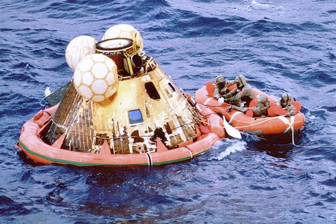 Divers ride ocean in raft next to space capsule