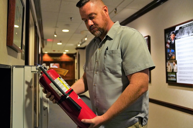Michael Burgess, assistant facility and safety manager, U.S. Transportation Command, evaluates a fire extinguisher during a safety inspection July 9 on the third floor of Building 1900 East.