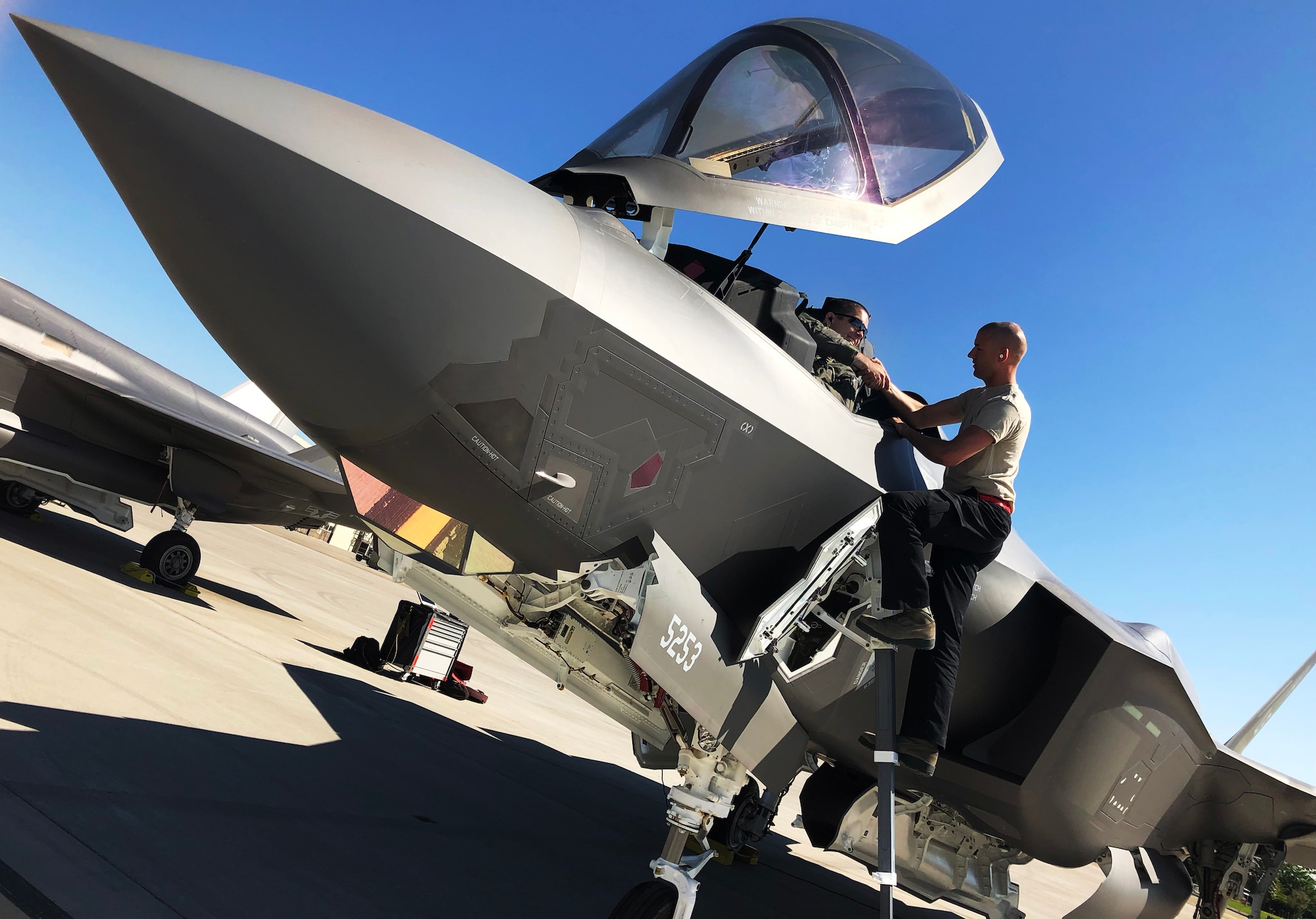 An F-35A maintainer hands Lt. Col. Christopher White his gear as he prepares for an engine check prior to the first sortie of the day July 11.The 388th Fighter Wing's 34th Fighter Squadron is operating out of Mountain Home AFB, Idaho, while Hill AFB's runway is under construction. (U.S. Air Force photo by Micah Garbarino)