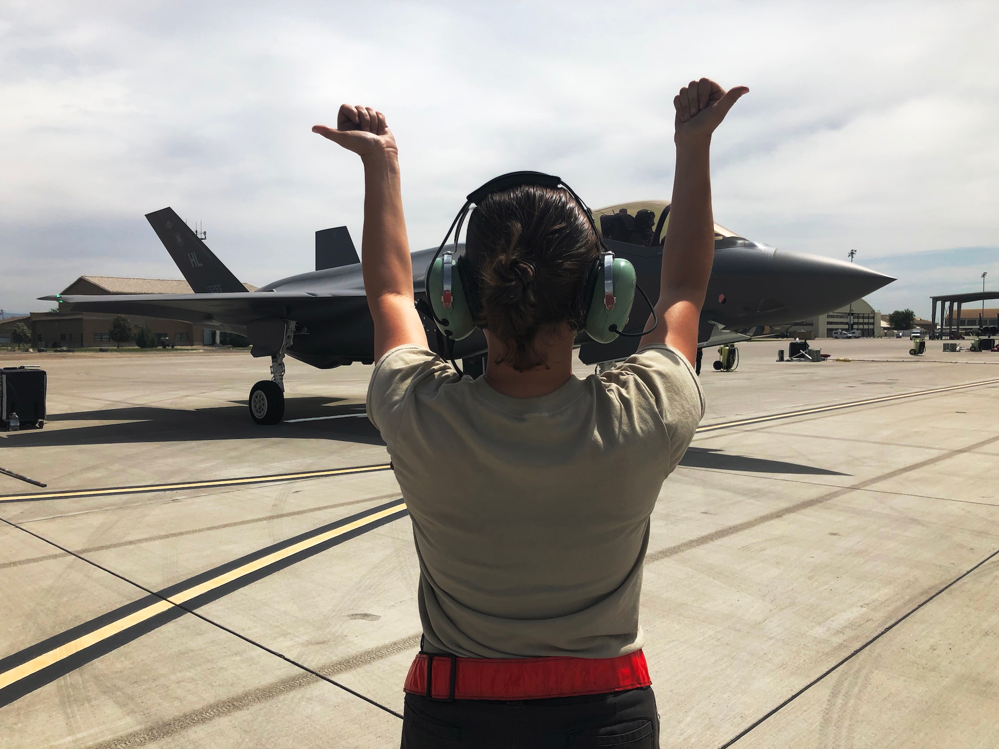 Senior Airman Cheyenne Rust, an F-35A crew chief with the 388th Fighter Wing's 34th Fighter Squadron, currently deployed to Mountain Home Air Force Base, Idaho, marshals a jet prior to the first sorties of the day July 10. (U.S. Air Force photo by Micah Garbarino)