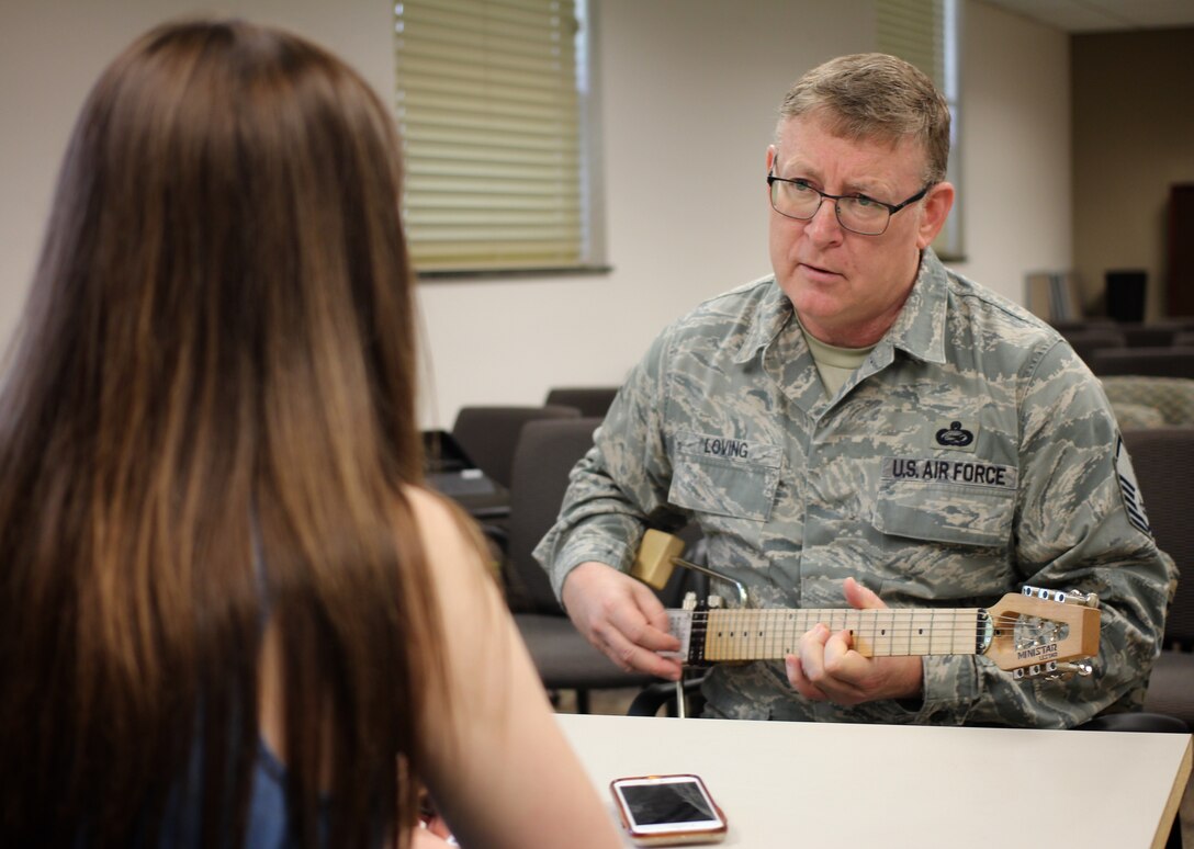 Master Sgt. Tony Loving has witnessed many squadron changes, as well as being involved in making improvement within military processes over time.  He plays a song while interviewer Kayla Prather listens and asks him questions on his work in 932nd Force Support Squadron.  (U.S. Air Force photo by Lt. Col. Stan Paregien)