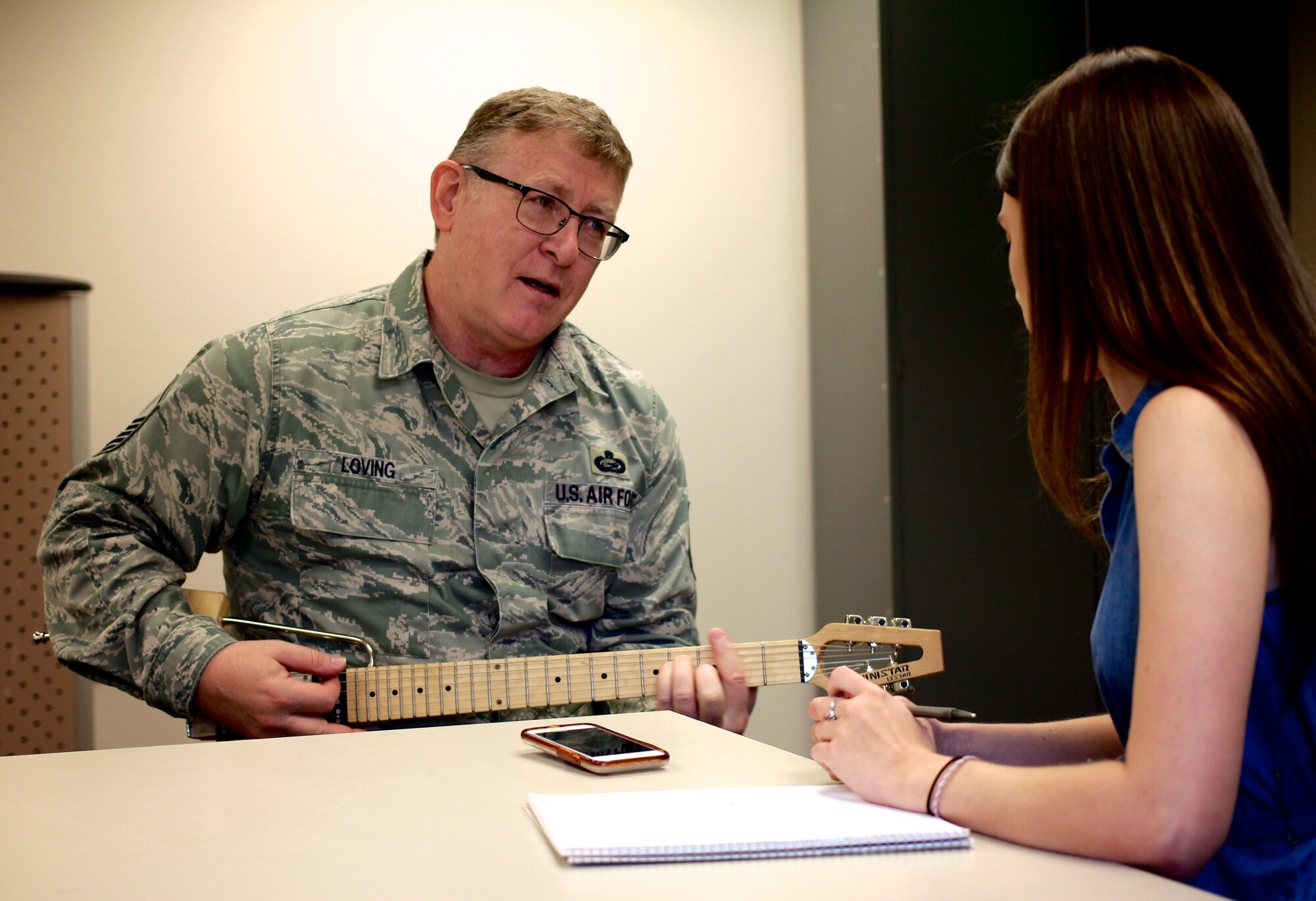 Master Sgt. Tony Loving plays a song while interviewer Kayla Prather listens and asks him questions on his work in 932nd Force Support Squadron.  (U.S. Air Force photo by Lt. Col. Stan Paregien)