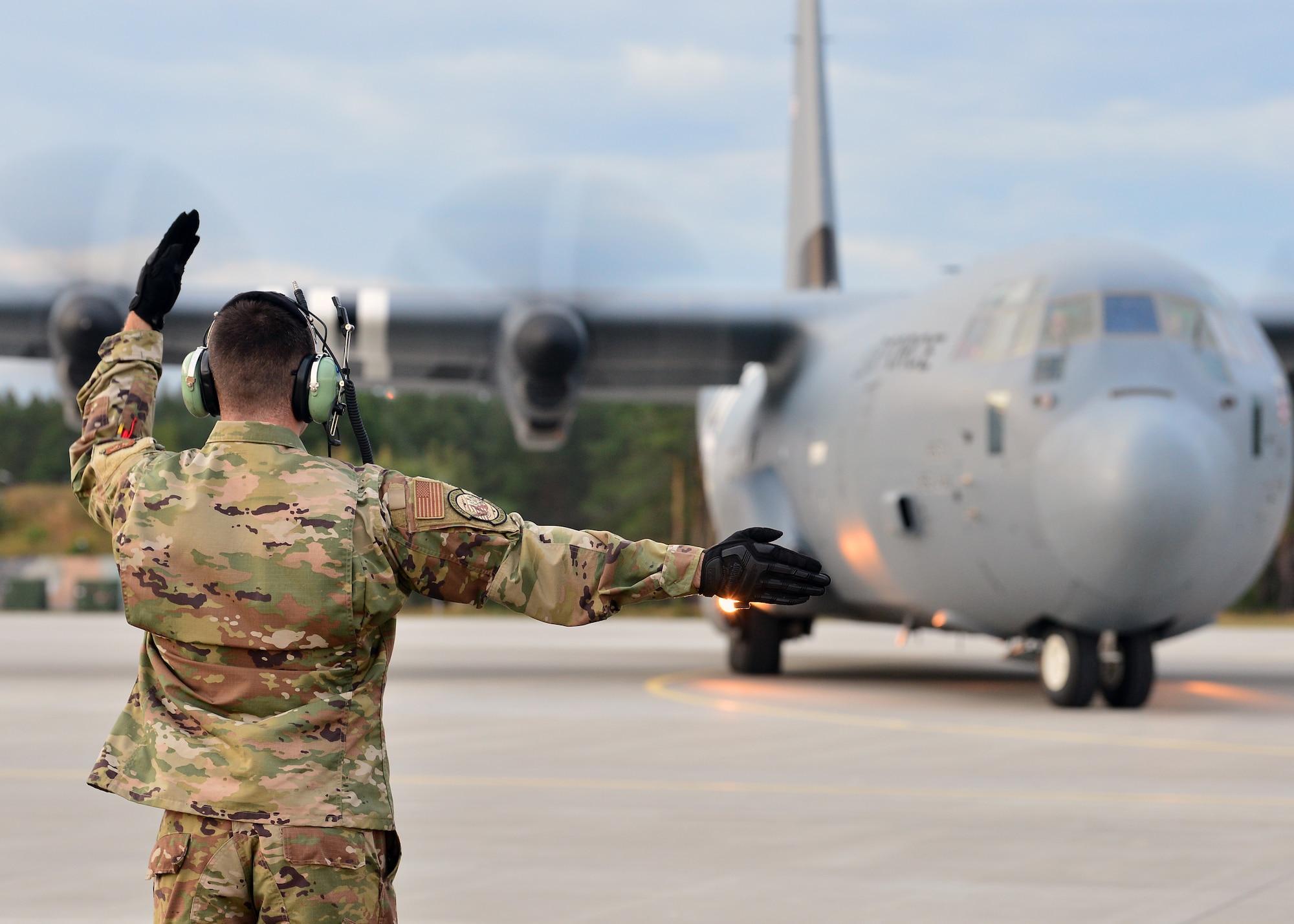 An Airman deployed with the 37th Airlift Squadron marshals a C-130J Super Hercules at Powidz Air Base, Poland, July 10, 2019. Approximately 80 Airmen and three aircraft deployed to Powidz Air Base in support of Aviation Rotation 19-3, a bilateral training exercise between the U.S. and Polish air forces. (U.S. Air Force photo by Staff Sgt. Jimmie D. Pike)