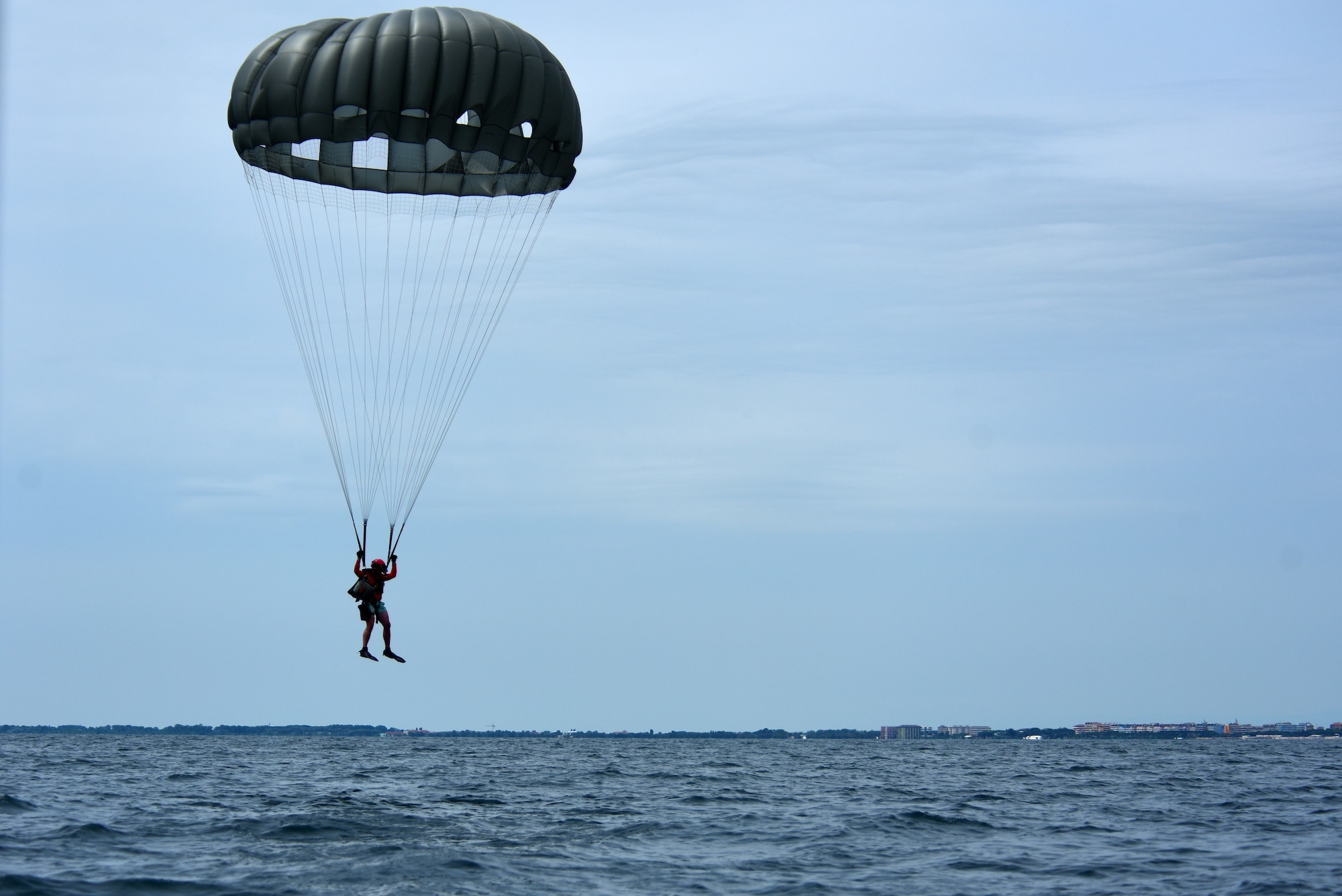 A U.S. Air Force pararescueman assigned to the 57th Rescue Squadron parachutes into the ocean during over-water parachute training off the coast of Italy, July 9, 2019. The Airmen partnered with C-130J Hercules aircraft and crews from Ramstein Air Base, Germany, in order to complete their quarterly parachute training. (U.S. Air Force photo by Staff Sgt. Kelsey Tucker)