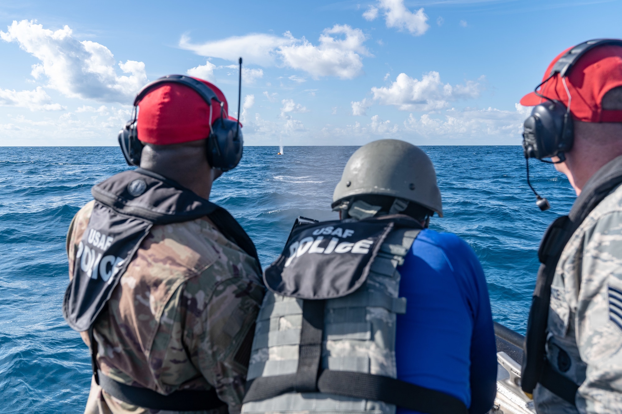 U.S. Air Force Tech. Sgt. Antonio J. Howard and Tech. Sgt. Randall D Perry, 6th Security Forces Squadron combat arms instructors, flank Senior Airman Bryan C. Scott, a 6th SFS marine patrolman, while he shoots an M240 machine gun at an orange target buoy 12 miles off the coast of St. Petersburg, Fla., July 2, 2019.