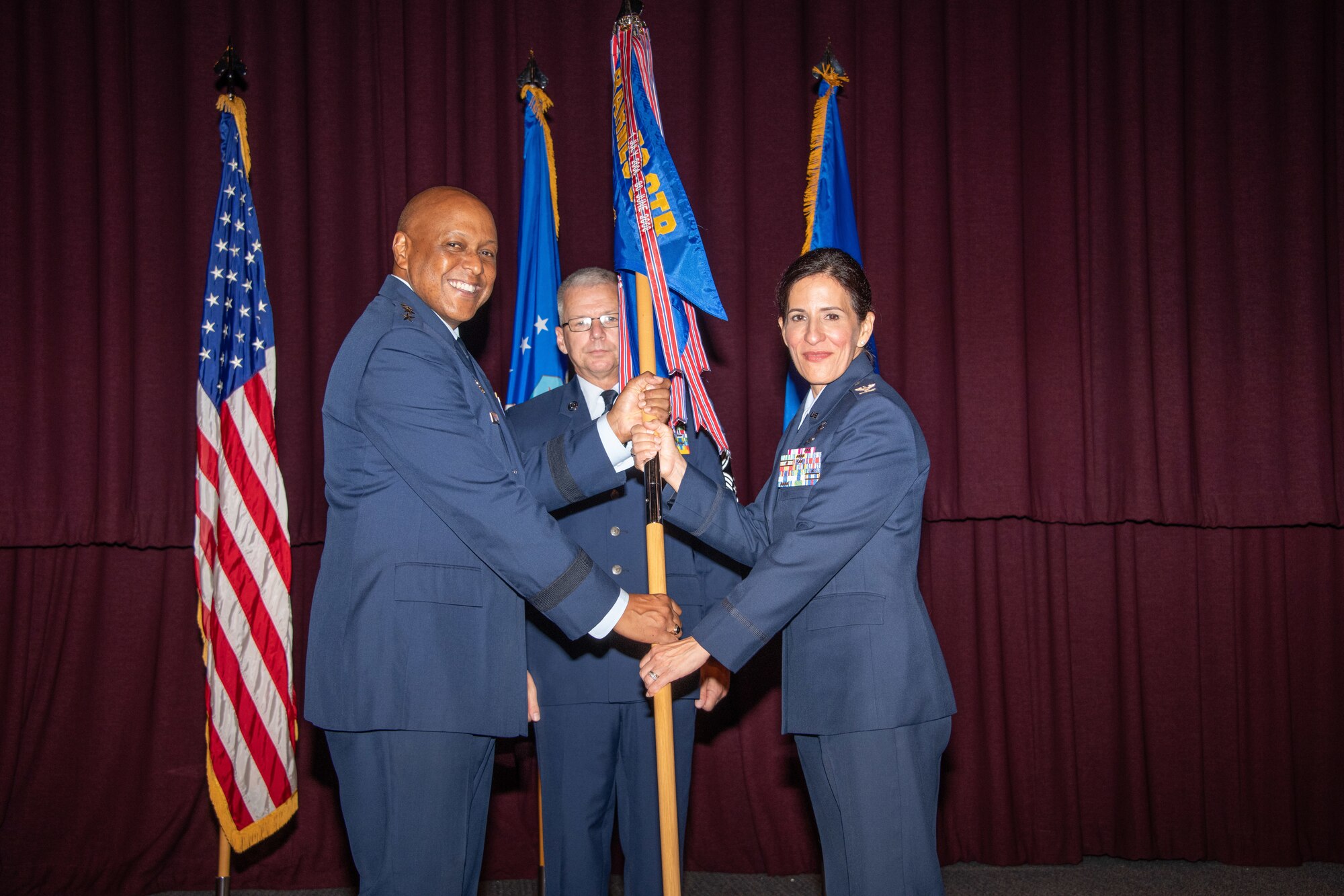 Lt. Gen. Anthony J. Cotton, Air University Commander and President, passes a guidon to Col. Kathryn A. Brown during her assumption of command for the Barnes Center July 11, 2019, at the Air Force Senior Noncommissioned Officer Academy Auditorium, Gunter Annex, Alabama. Brown received her commission in 1995 while attending Arizona State University. She served as the commander for the 11th Operations Group, Joint Base Andrews, Maryland, before assuming command of the center.