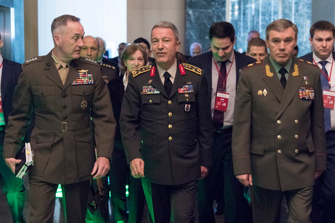 Three general officers walk in a hall.