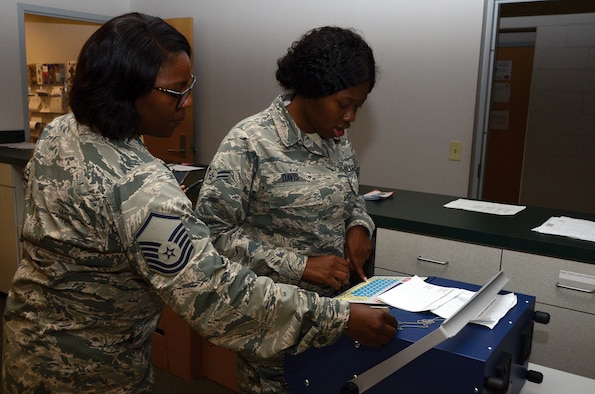 Master Sgt. Siearra Williams, 445th Force Support Squadron NCO in charge of customer support, teaches Airman 1st Class Tyra Davis, customer support assistant, how to use the dog tag machine June 20, 2019. Davis enters a service member’s information that will be engraved into small metal plates