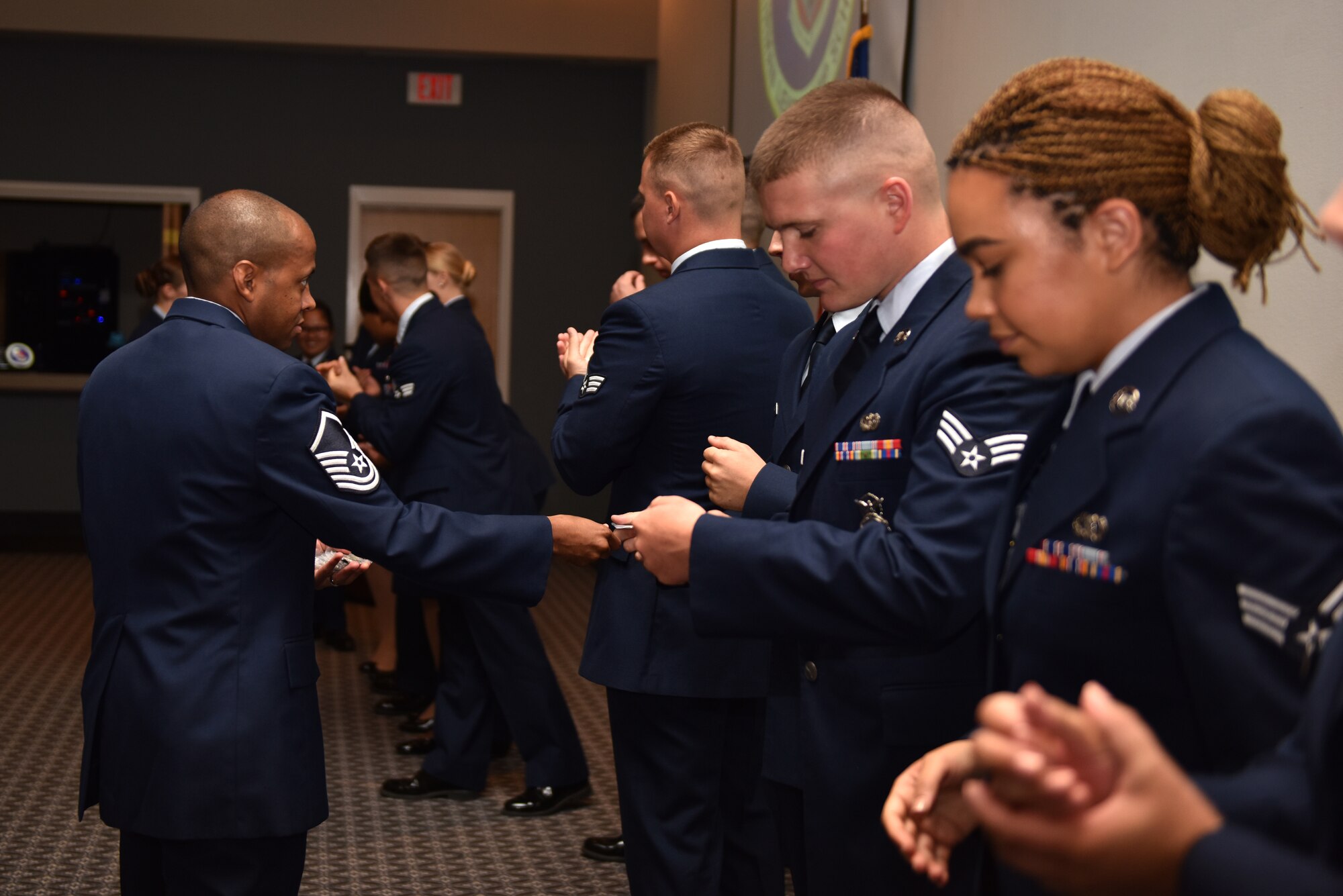 U.S. Air Force Master Sgt. Sheraz Cedeno, 17th Training Wing Airman Leadership School commandant, coins and congratulates graduates of class 19-E after their graduation held at the event center on Goodfellow Air Force Base, Texas, July 11, 2019. Graduates from the leadership course will go on to become first-line supervisors at their workplaces, putting into practice the skills they learned in class. (U.S. Air Force photo by Senior Airman Seraiah Wolf/Released)
