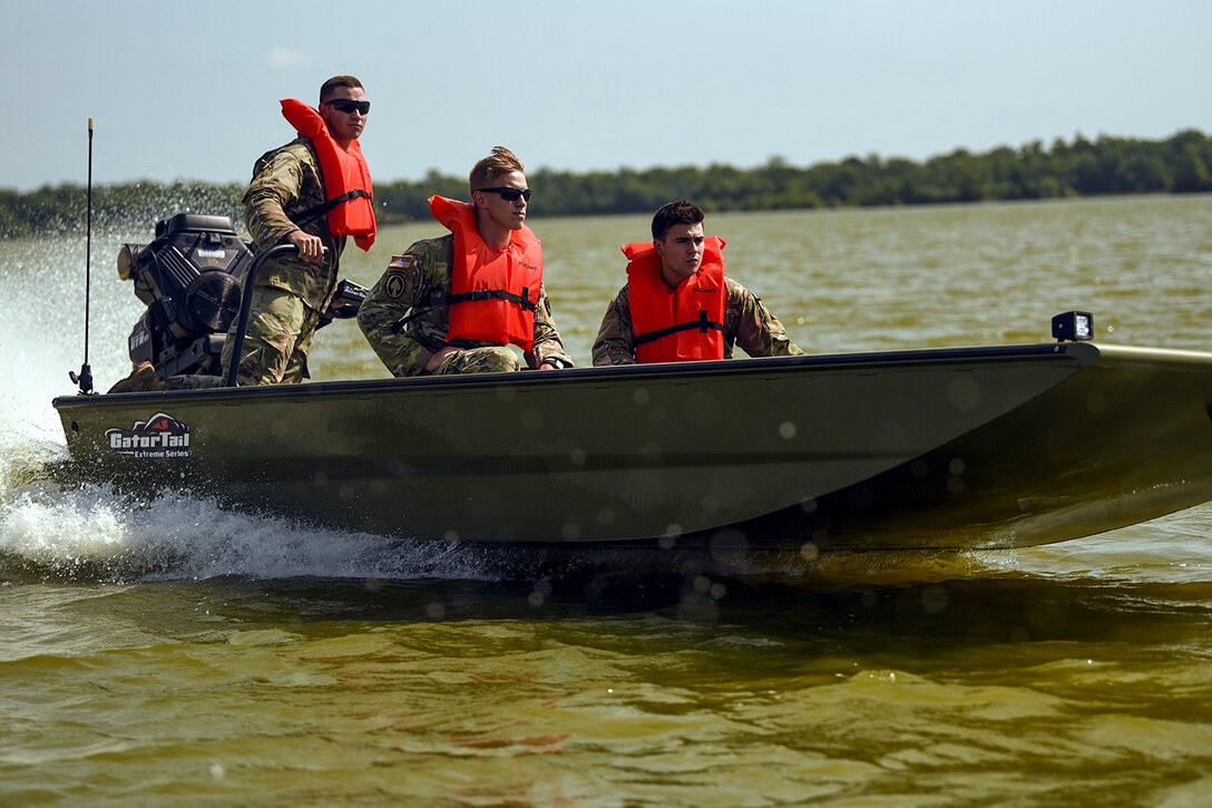 Three guardsman travel on greenish water in a motorboat.