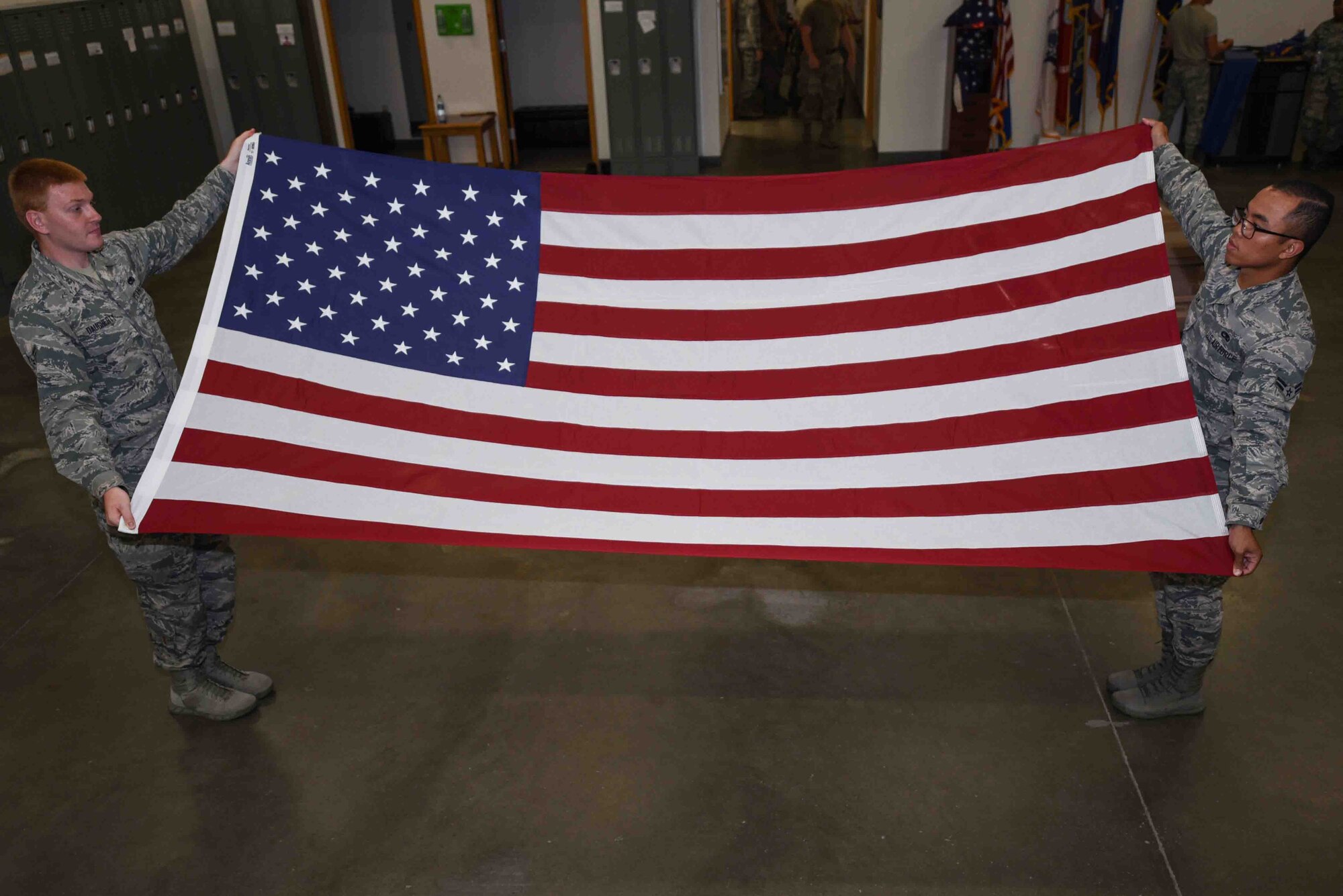 Airman 1st Class Phong Lam and Airman 1st Class Travis Daugherty, 22nd Force Support Squadron honor guardsmen, practice folding the flag July 9, 2019, at McConnell Air Force Base, Kan. McConnell’s Honor Guard trains five days a week to practice for events such as military retirements, change of command ceremonies and community events. (U.S. Air Force photo by Airman 1st Class Alexi Myrick)