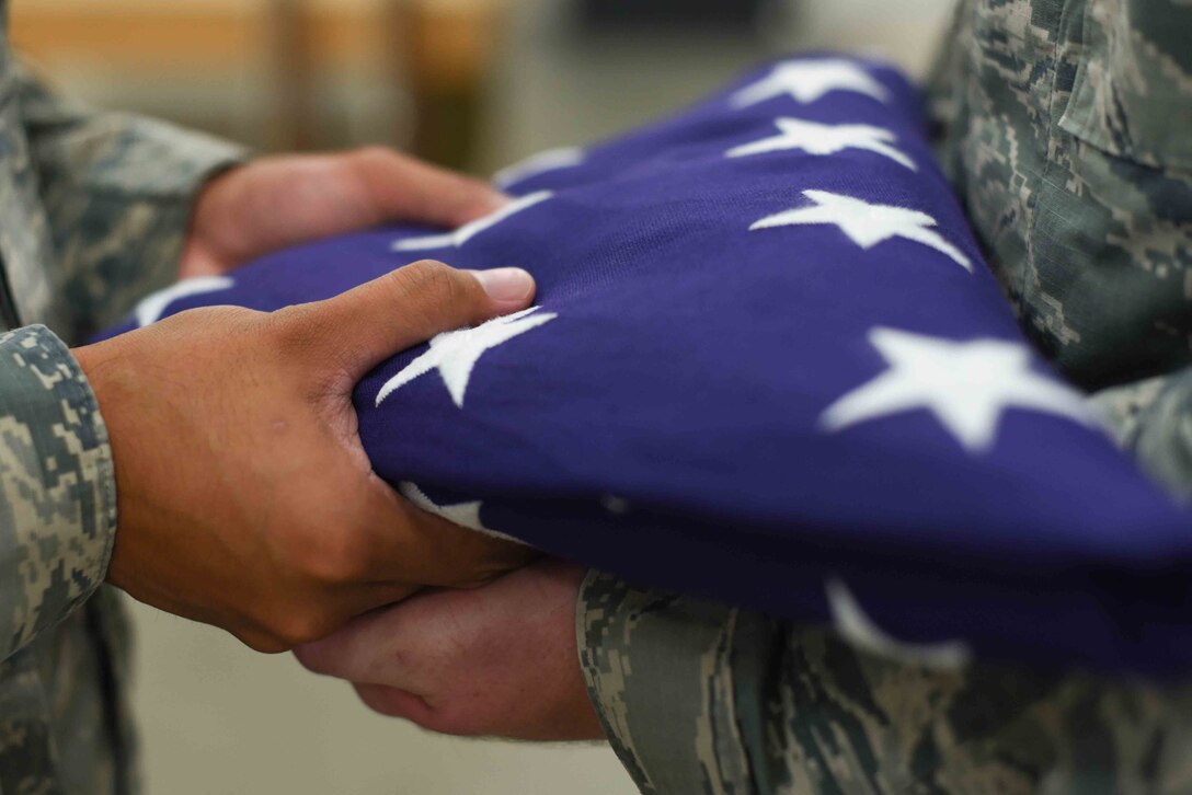 Airman 1st Class Phong Lam, 22nd Force Support Squadron honor guardsman, hands the flag to Airman 1st Class Travis Daugherty, 22nd FSS honor guardsman, during practice July 9, 2019, at McConnell Air Force Base, Kan. Members of McConnell’s Honor Guard participated in the fifth annual Red, White and Boom event held on July 4, 2019. This event was held to celebrate the United States’ Independence Day and included concerts, food trucks and fireworks. (U.S. Air Force photo by Airman 1st Class Alexi Myrick)