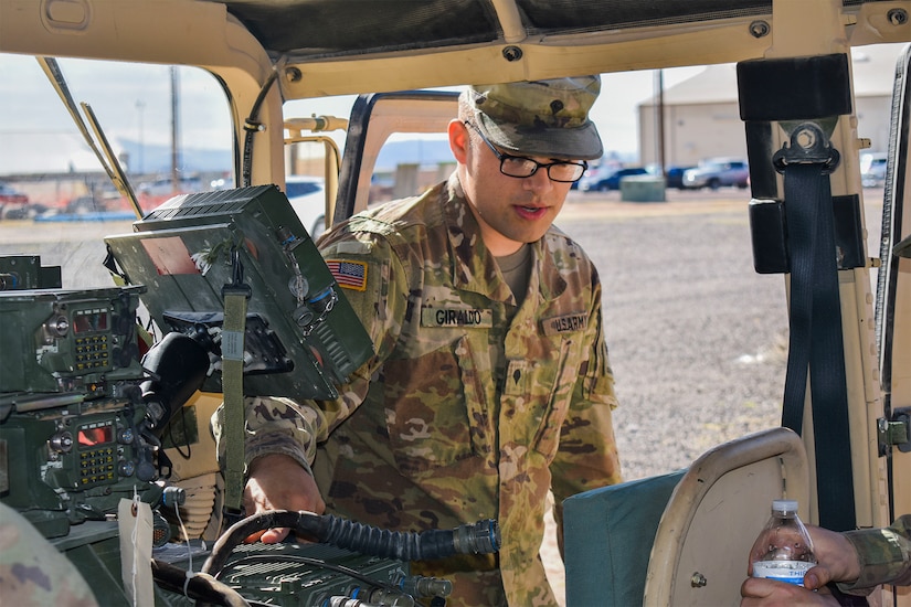 A soldier rests his hand on a radio in a tactical vehicle.