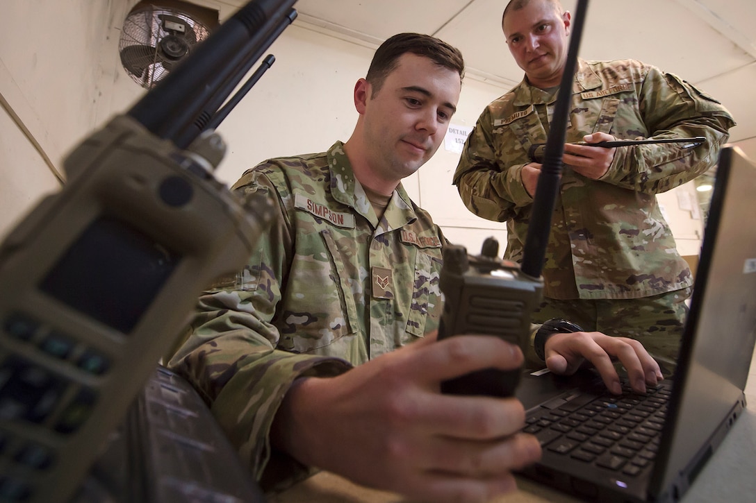 Airmen operate a radio and a laptop.