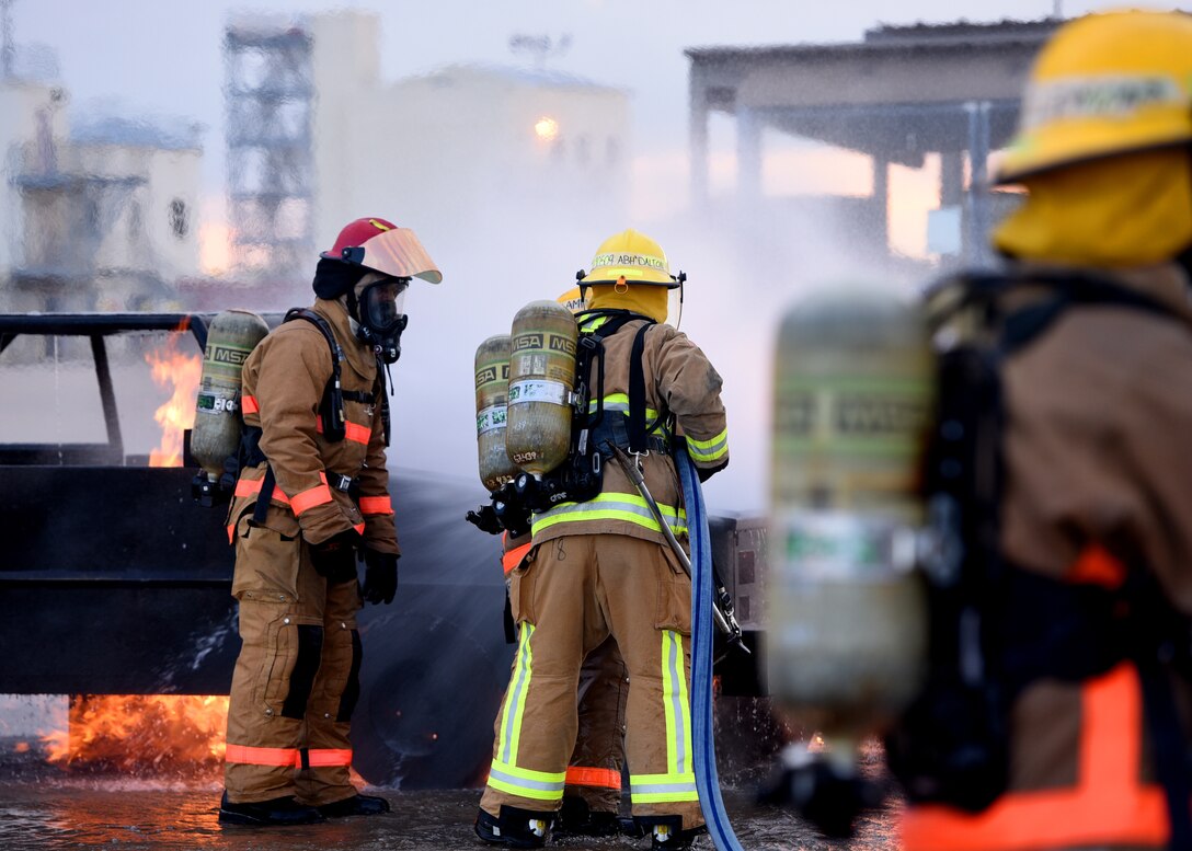 U.S. Army Staff Sgt. Roderick Dixon, 169th Engineer Battalion instructor, coaches his students on the different angles to direct the fire hose to put out a mock vehicle fire outside the Louis F. Garland Department of Defense Fire Academy on Goodfellow Air Force Base, Texas, July 11, 2019. Dixon teaches a 20-day Fire Protection course where students learn with a hands on approach to a variety of burning environments, such as vehicle, ground, and building fires. (U.S. Air Force Photo by Airman 1st Class Abbey Rieves/Released)