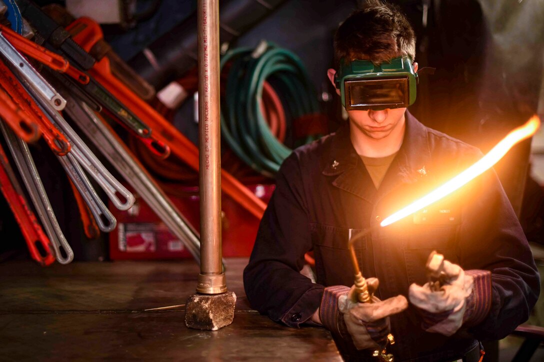 A sailor lights a torch.