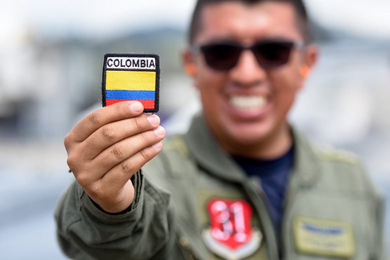 A man holds up a patch of the Colombian flag.