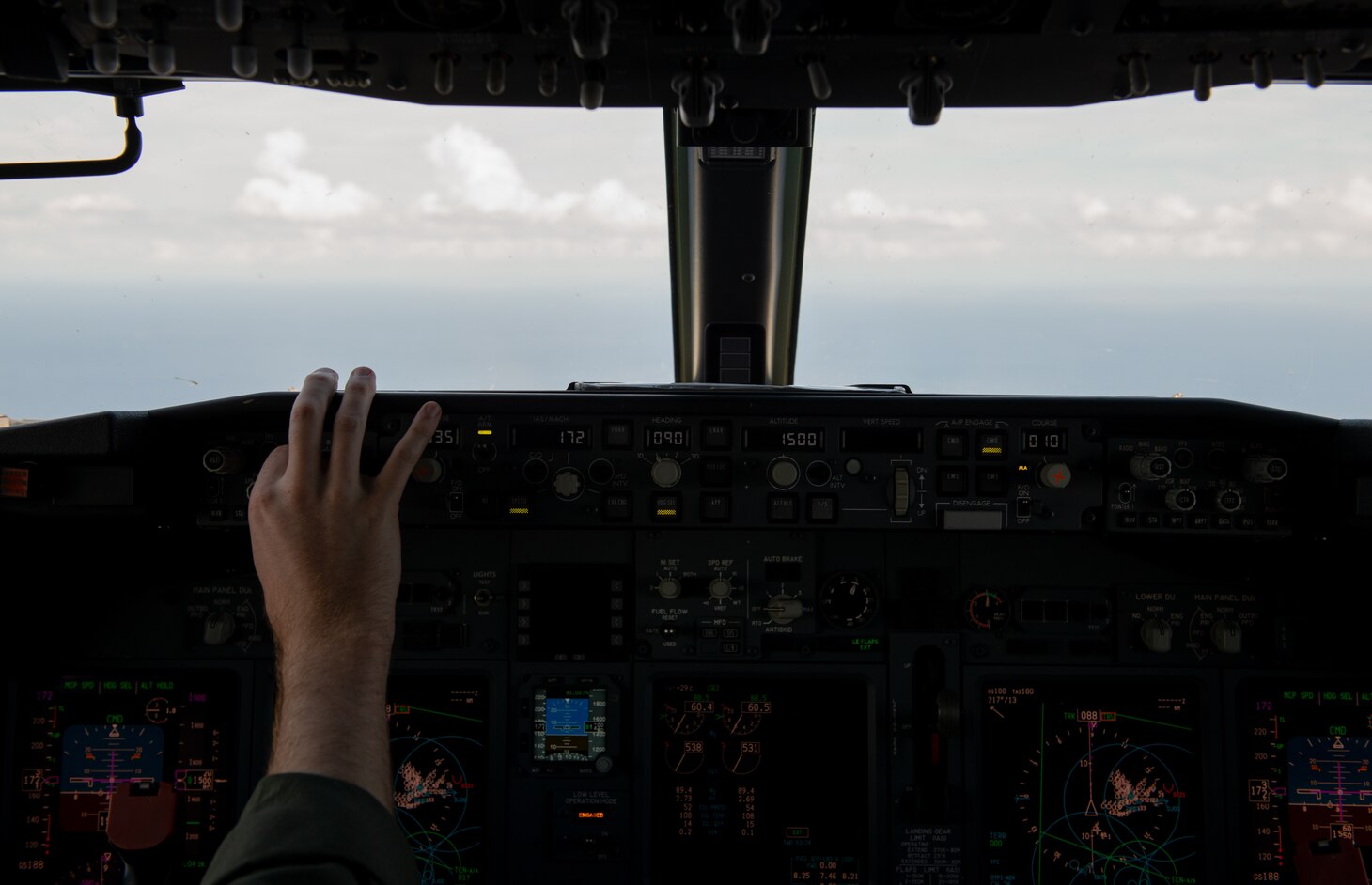 A hand reaching towards the aircraft control buttons