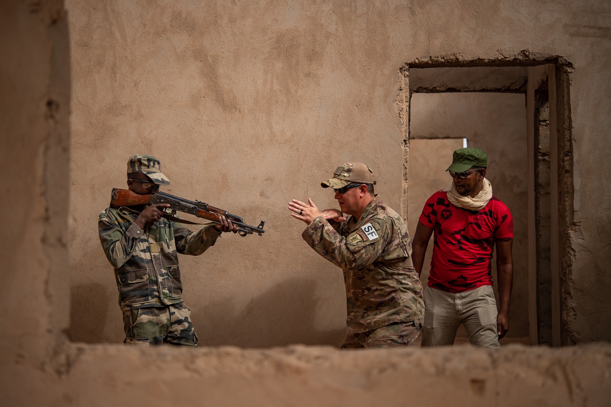 U.S. Air Force Tech. Sgt. Tyler Torr, 409th Expeditionary Security Forces Squadron air advisor, center, gives instructions to a Niger Armed Forces (French language: Forces Armées Nigeriennes) member while Salah, Combined Defense Operations Center interpreter, translates the instructions during a training exercise at the FAN compound on Nigerien Air Base 201 in Agadez, Niger, July 10, 2019. The training enables both forces to improve interoperability, and also helps the Nigeriens to protect themselves during deployments. (U.S. Air Force photo by Staff Sgt. Devin Boyer)