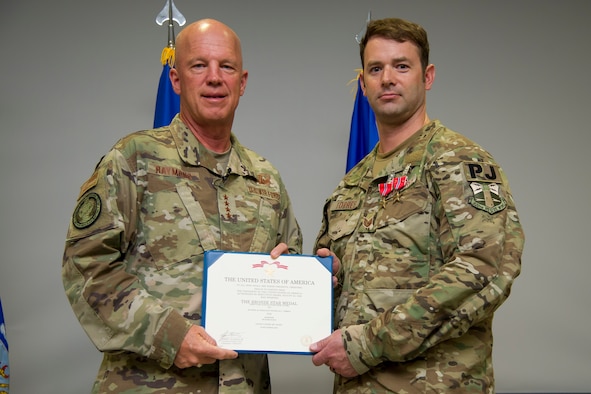 Air Force Space Command commander, Gen. John W. "Jay" Raymond, presents two bronze star medals, including one with valor, to a traditional reservist, Tech. Sgt. Nick Torres.