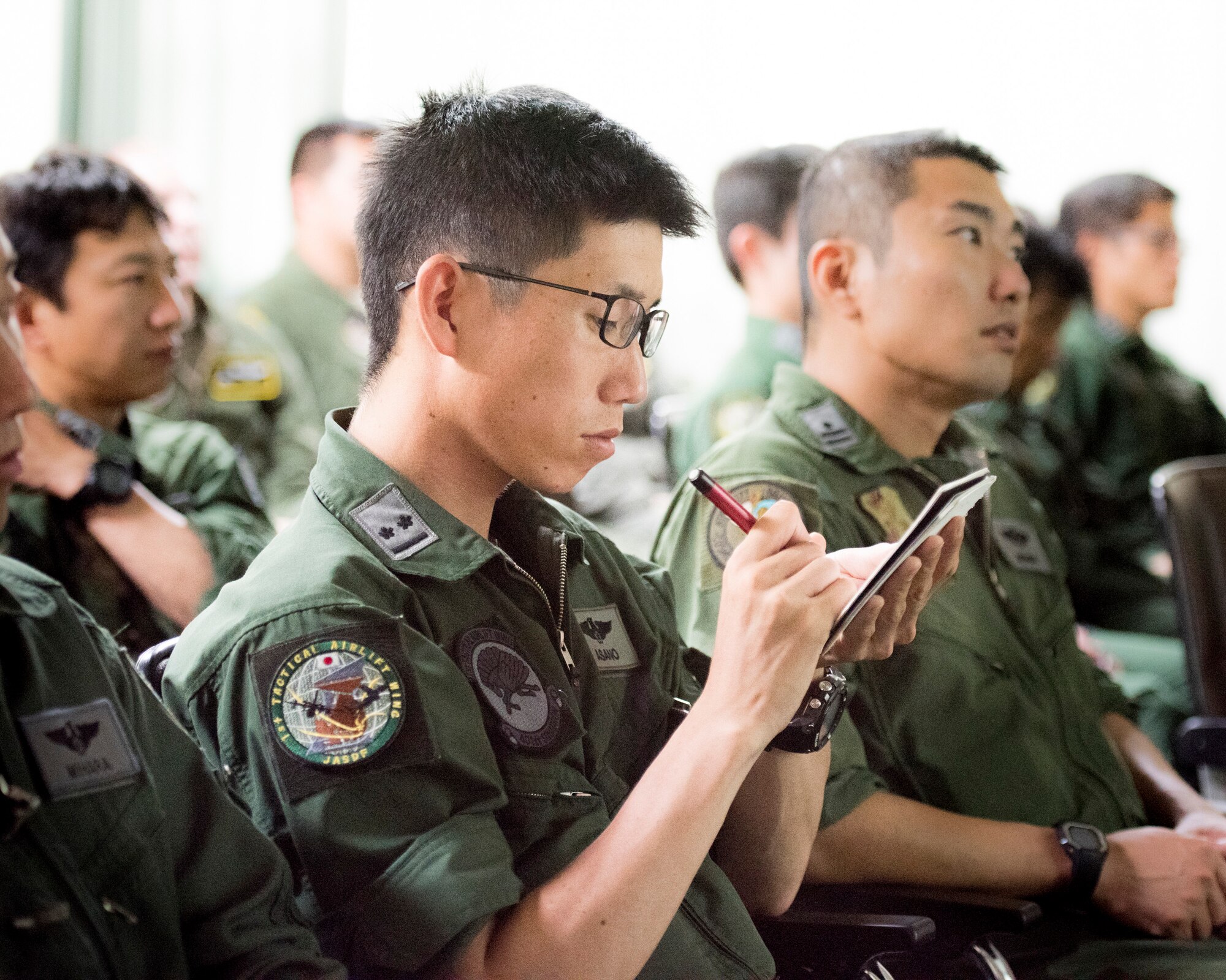 A member from the Japan Air Self-Defense Force makes a note during a briefing by members from 374th Airlift Wing at Iruma Air Base, Japan, July 10, 2019