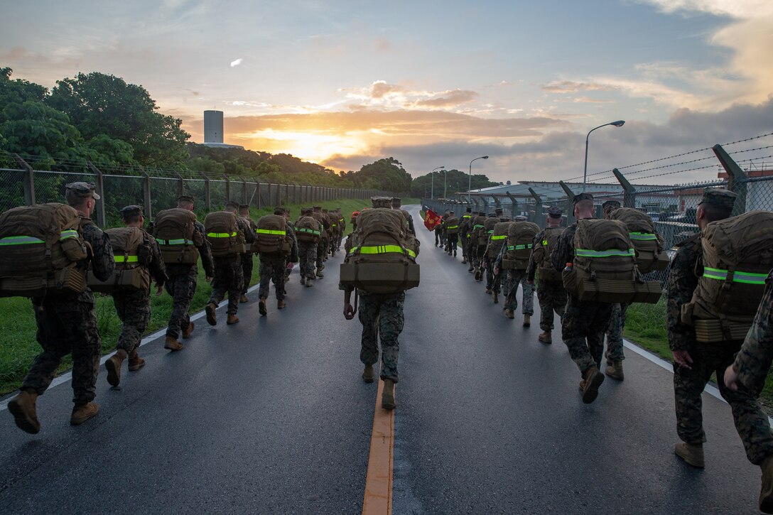 A group of Marines walk up a street at twilight.