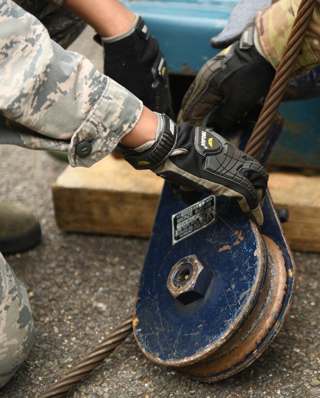 Airman from the 48th and 100th Logistics Readiness Squadron set up a pulley and cables from a tow truck to pull a 10K all-terrain forklift during a Readiness Honed In Operations training day at RAF Lakenheath, England, July 13, 2019. Airmen received in-class training in conjunction with hands-on training such as to self-aid buddy care, advanced vehicle recovery using a tow truck and land navigation maps. (U.S. Air Force photo by Senior Airman Luke Milano)