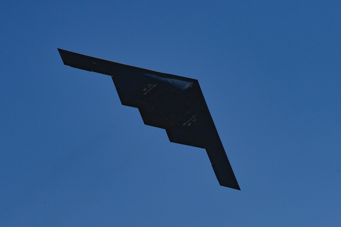 A B-2 Spirit is seen in silhouette from below as it performs a low flyover during the 2019 Wings Over Whiteman Air & Space Show at Whiteman Air Force Base, Missouri, June 15, 2019. The B-2 fleet is operated by the 509th Bomb Wing. During the air show, pyrotechnics simulated notional explosives for spectators on the ground. (U.S. Air Force photo by Tech. Sgt. Alexander W. Riedel)